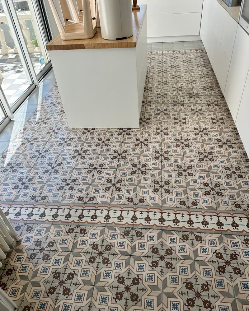 Carreaux de ciment à motif ancien autour d'un îlot de cuisine.