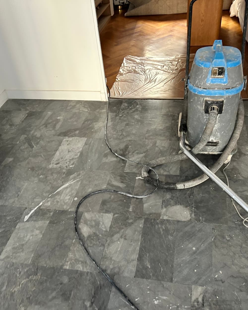 Sol de cuisine en marbre gris pendant le chantier, poussière et aspirateur.