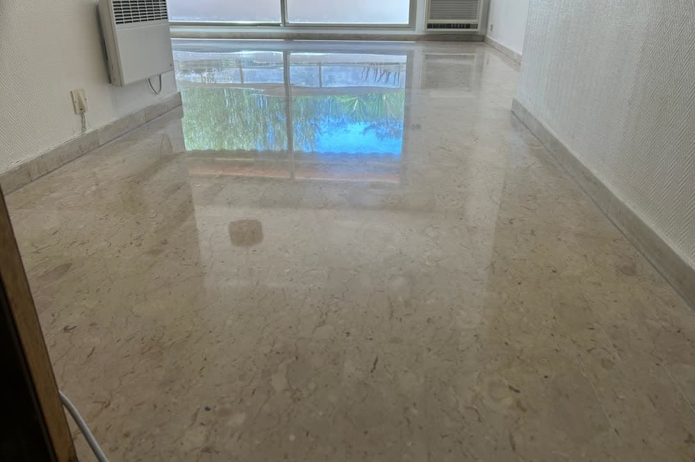 Marbre beige poli dans un appartement, reflets de la fenêtre.