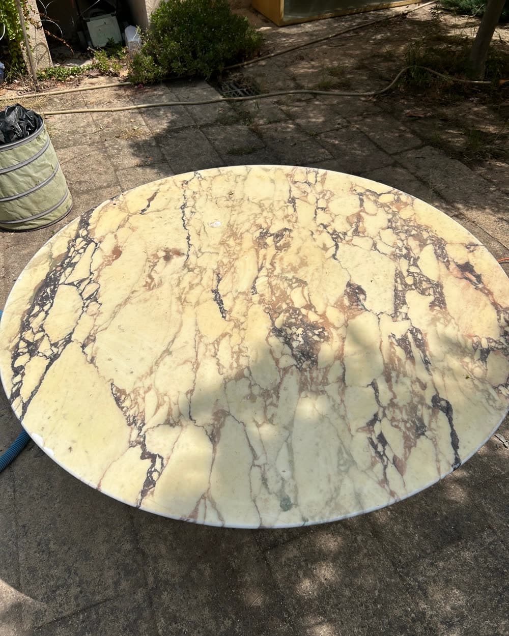 Table ronde en marbre, terne et tachée, avant.